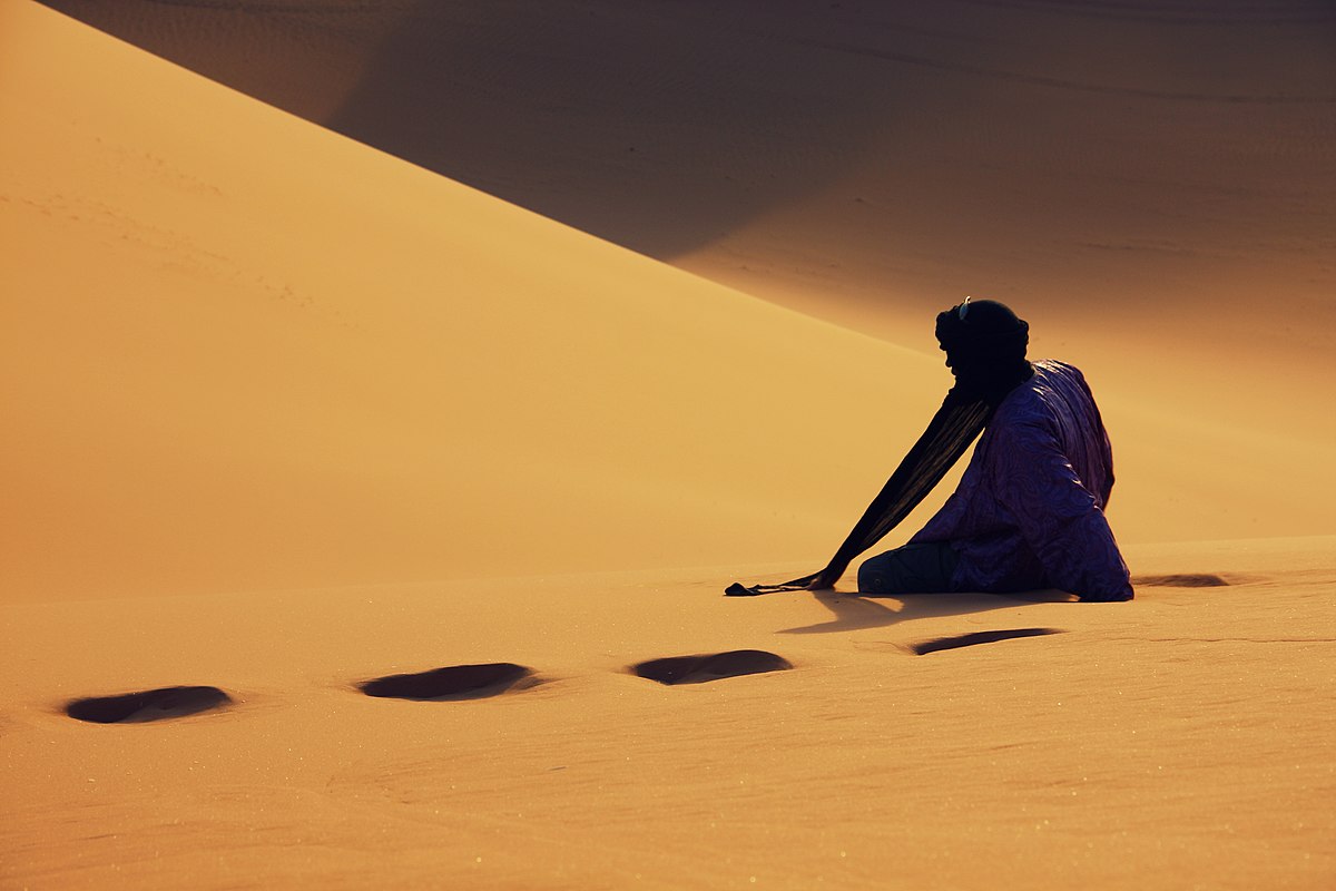 Un nomade assis dans le sable.